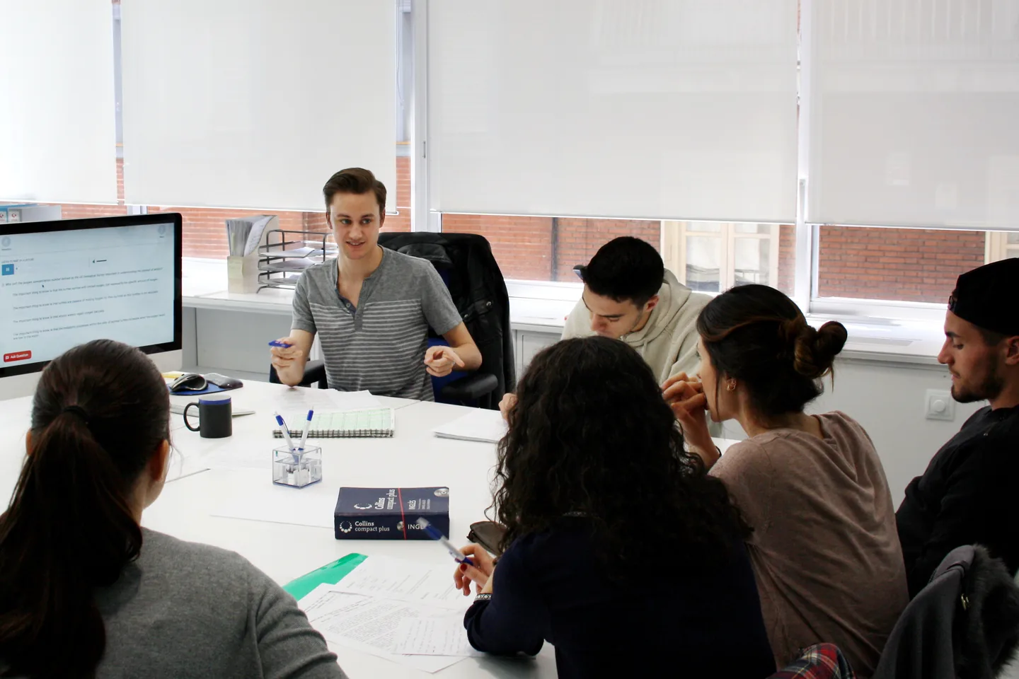 A classroom session around a table with a computer at Exam Madrid Academy.